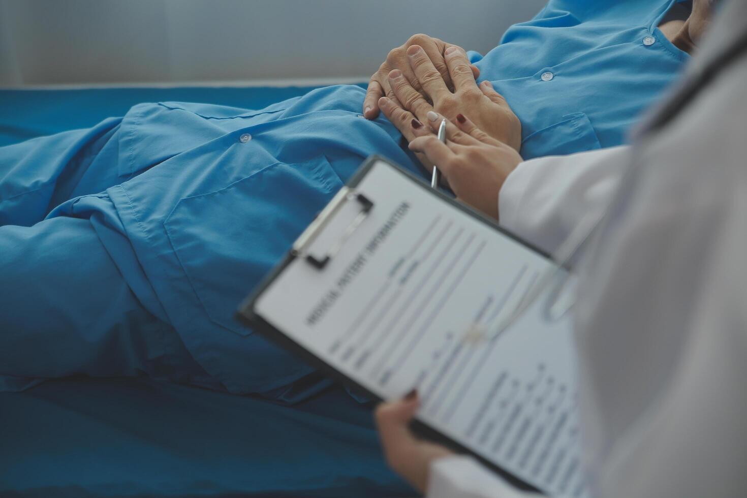 Hospitalized man lying in bed while doctor checking his pulse. Female physician examining male patient in hospital room. photo