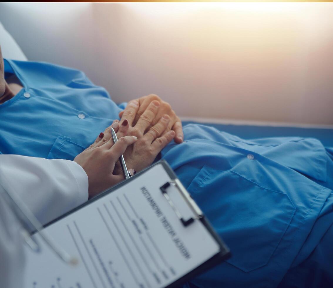 Hospitalized man lying in bed while doctor checking his pulse. Female physician examining male patient in hospital room. photo