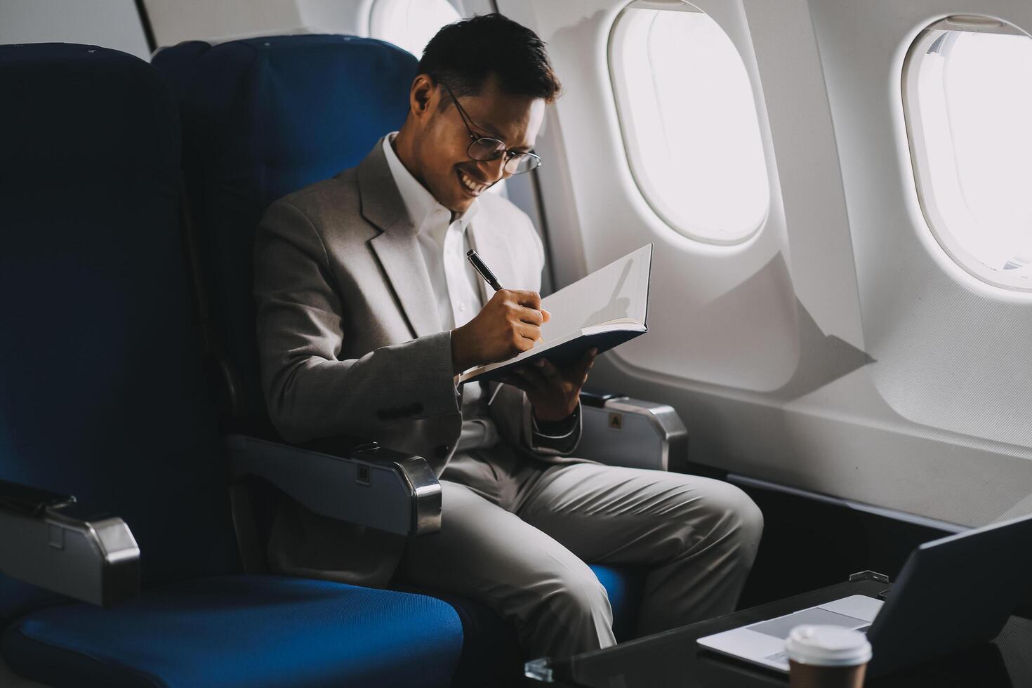 Airplane, travel and portrait of businessman working on laptop computer and smartphone while sitting in airplane. photo