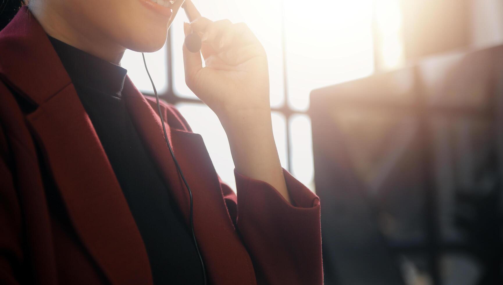 Friendly female helpline operator in call center. Young woman working in call center and holding microphone on headset with hand. photo
