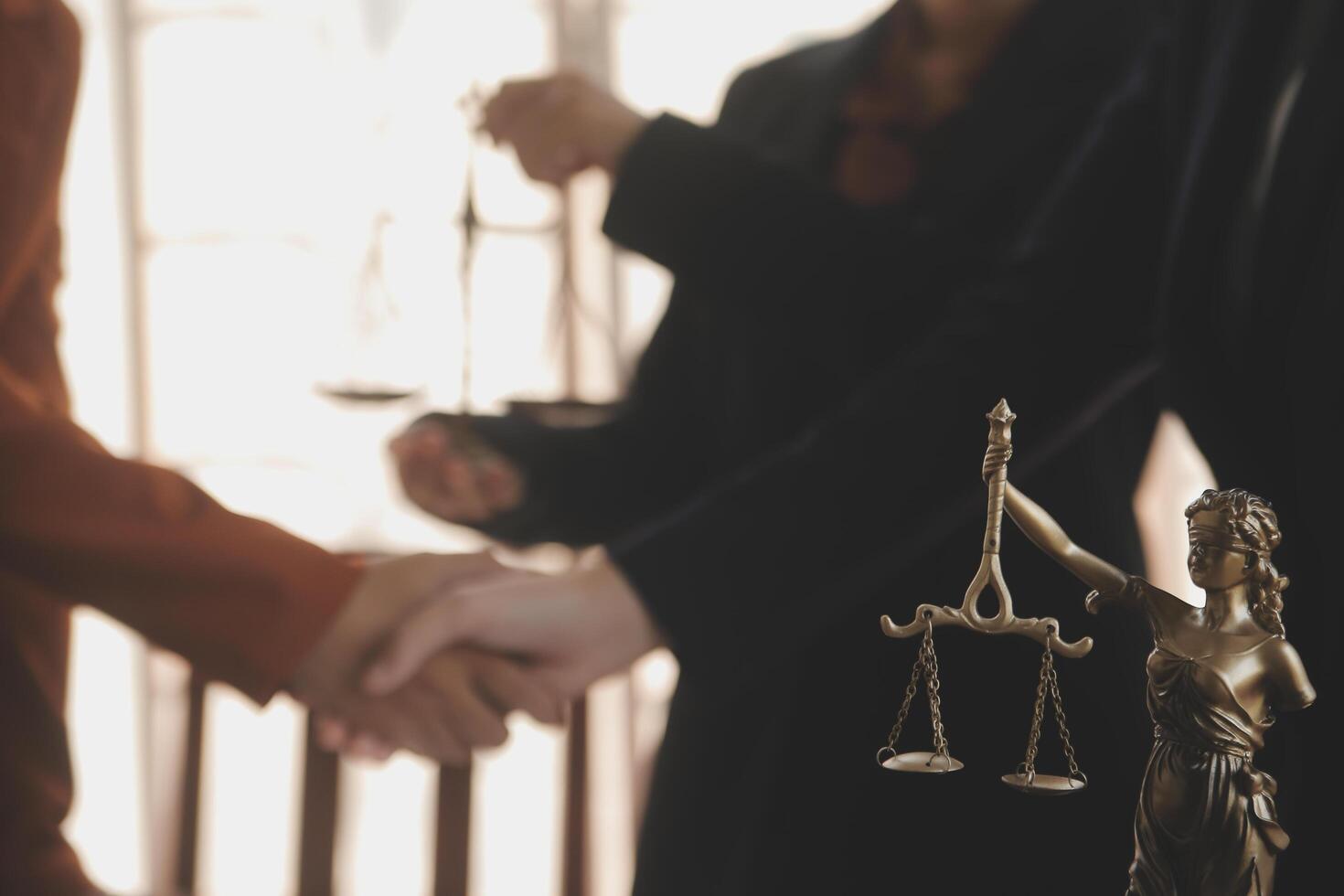 Lawyer shaking hands with a client making about documents, contracts, agreements, cooperation agreements with a female client at the lawyer's desk and a hammer at the table. photo