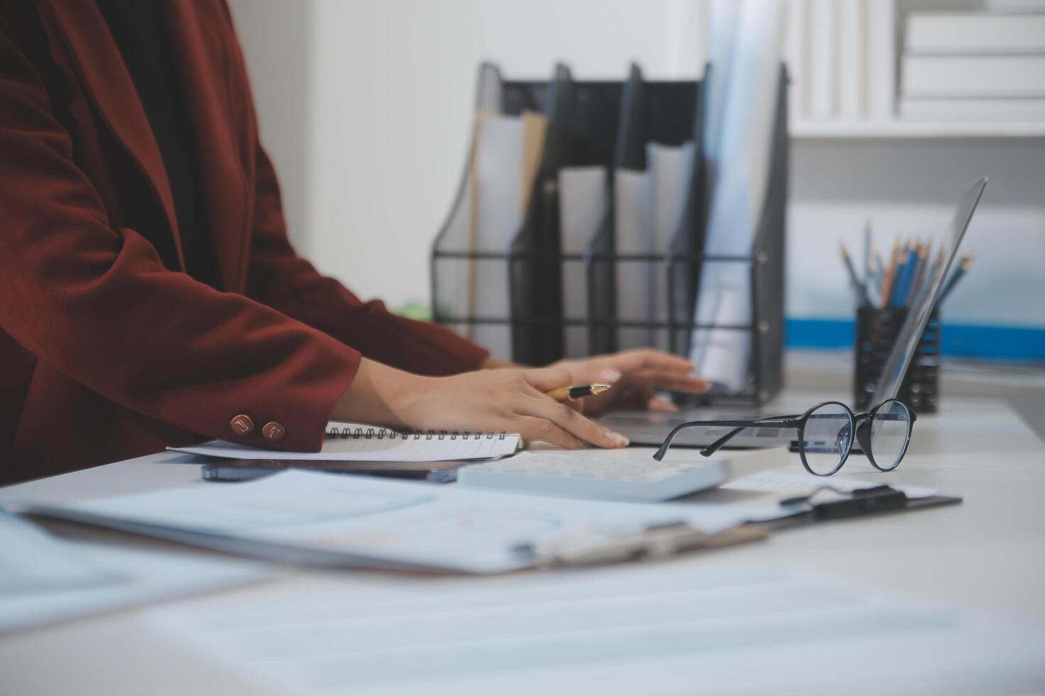 Cropped image of professional businesswoman working at her office via laptop, young female manager using portable computer device while sitting at modern loft, flare light, work process concept photo