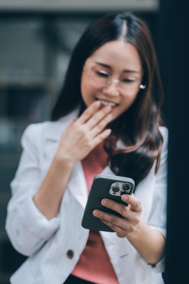 Portrait of a happy Asian businesswoman using mobile phone indoor, Asian businesswoman working in modern office. photo