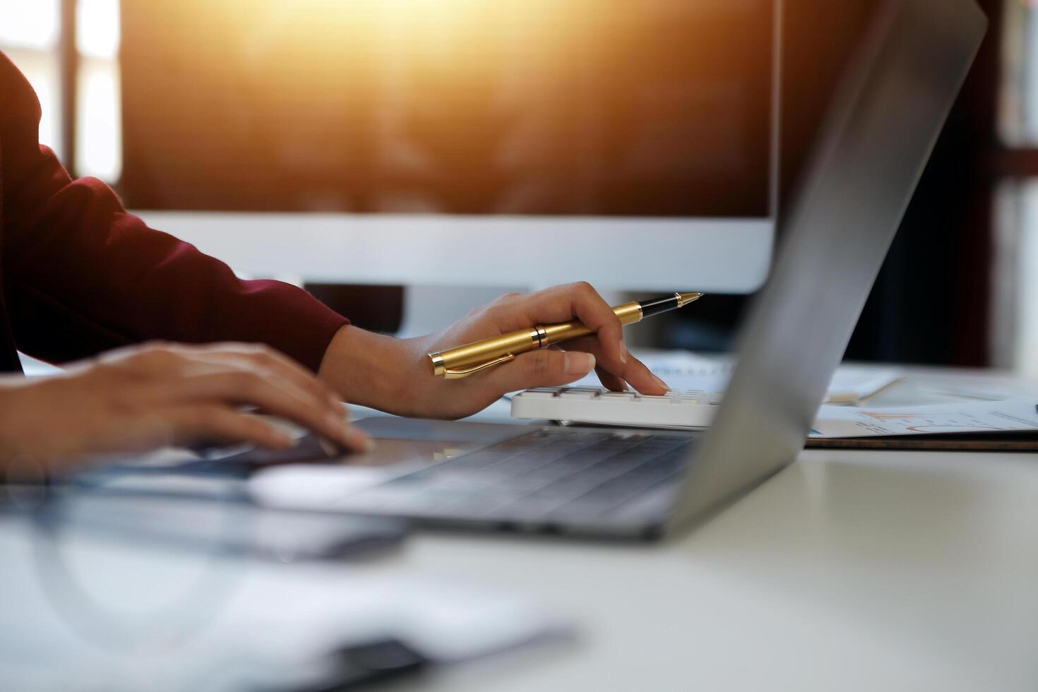 Cropped image of professional businesswoman working at her office via laptop, young female manager using portable computer device while sitting at modern loft, flare light, work process concept photo