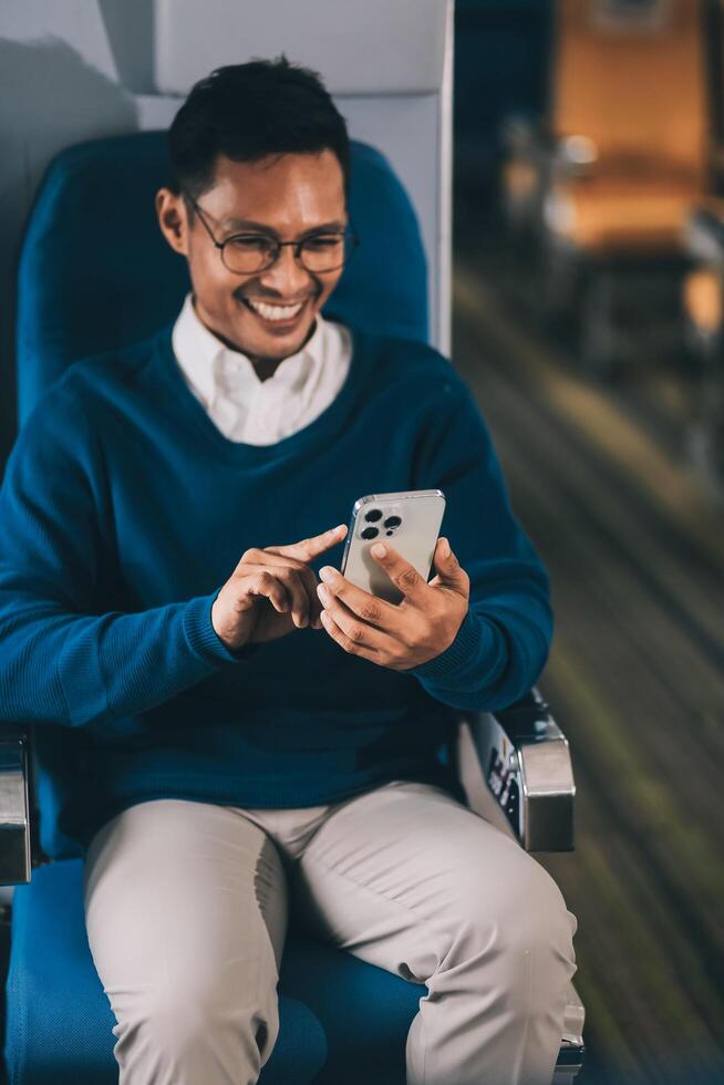 Man with dark hair is reading text message on mobile phone and speaking by phone during flying in the airplane photo