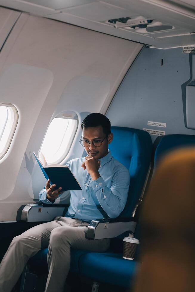 Airplane, travel and portrait of businessman working on laptop computer and smartphone while sitting in airplane. photo