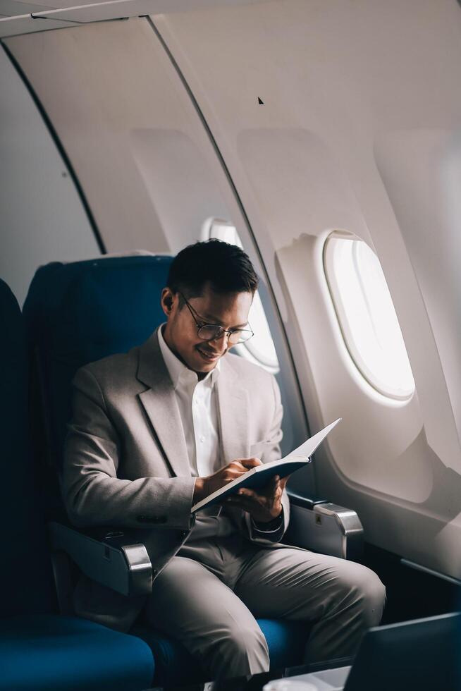 Airplane, travel and portrait of businessman working on laptop computer and smartphone while sitting in airplane. photo