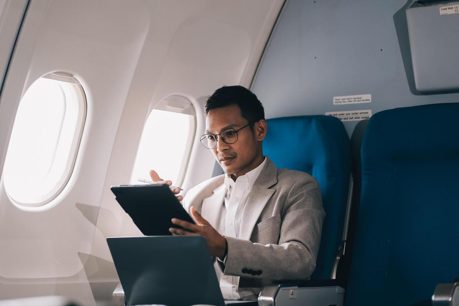 Airplane, travel and portrait of businessman working on laptop computer and smartphone while sitting in airplane. photo