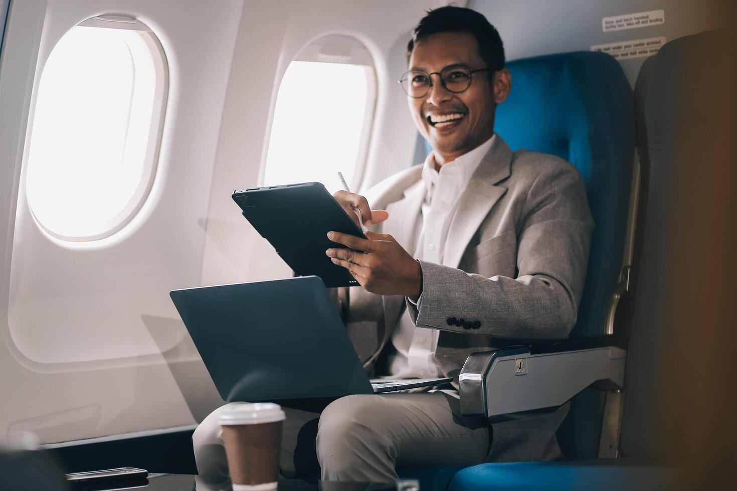 Airplane, travel and portrait of businessman working on laptop computer and smartphone while sitting in airplane. photo