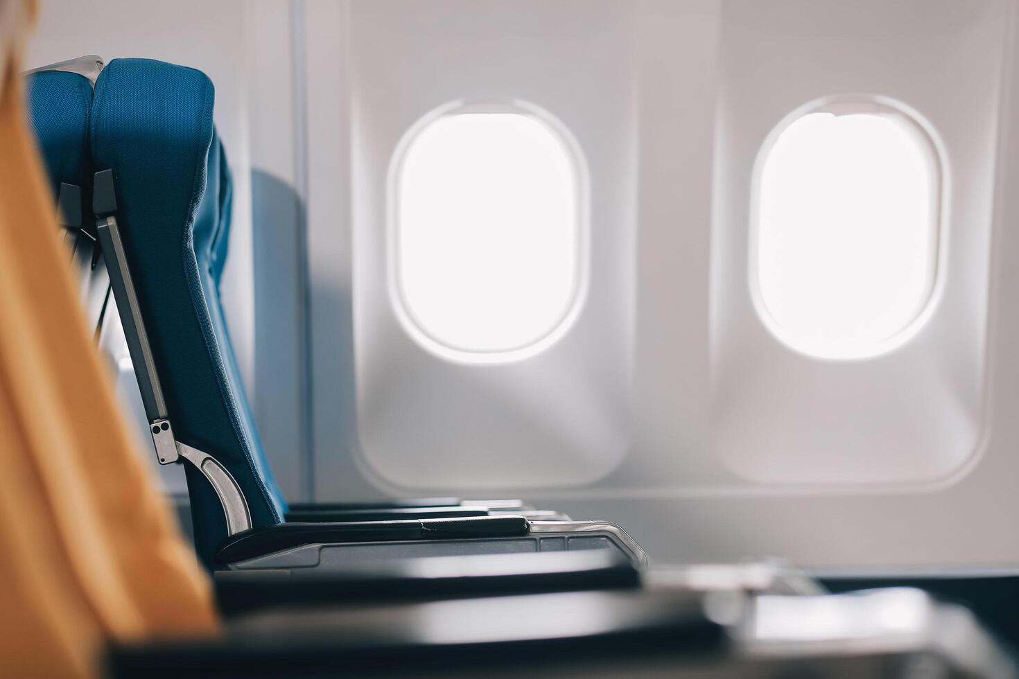 Side view millennial businessman drinking coffee, and using laptop while sitting comfortable seat on airplane cabin photo