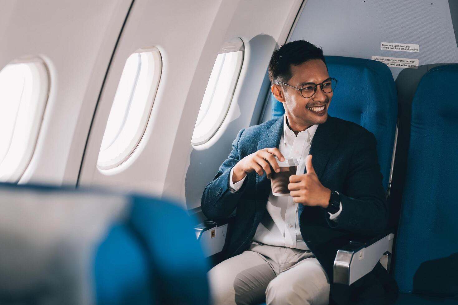 Satisfied businessman passenger drinking hot coffee while sitting on comfortable seat during business travel flight photo