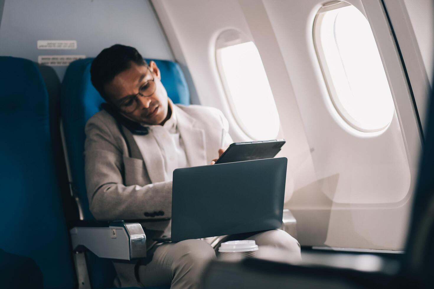 Airplane, travel and portrait of businessman working on laptop computer and smartphone while sitting in airplane. photo