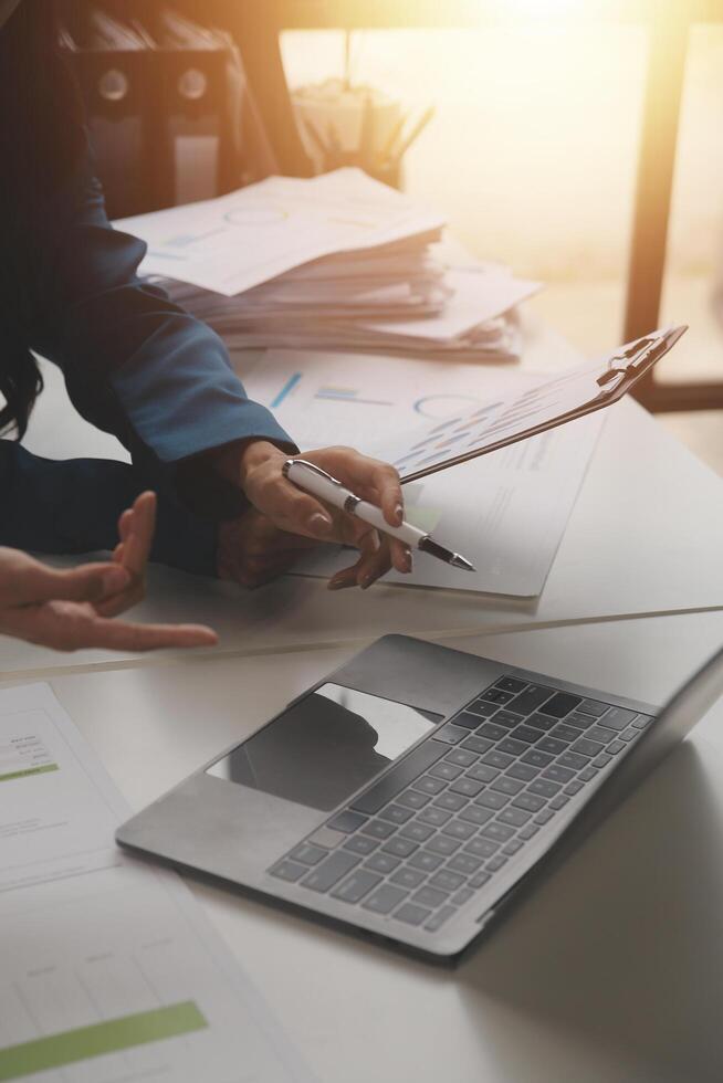 Group of confident business people point to graphs and charts to analyze market data, balance sheet, account, net profit to plan new sales strategies to increase production capacity. photo