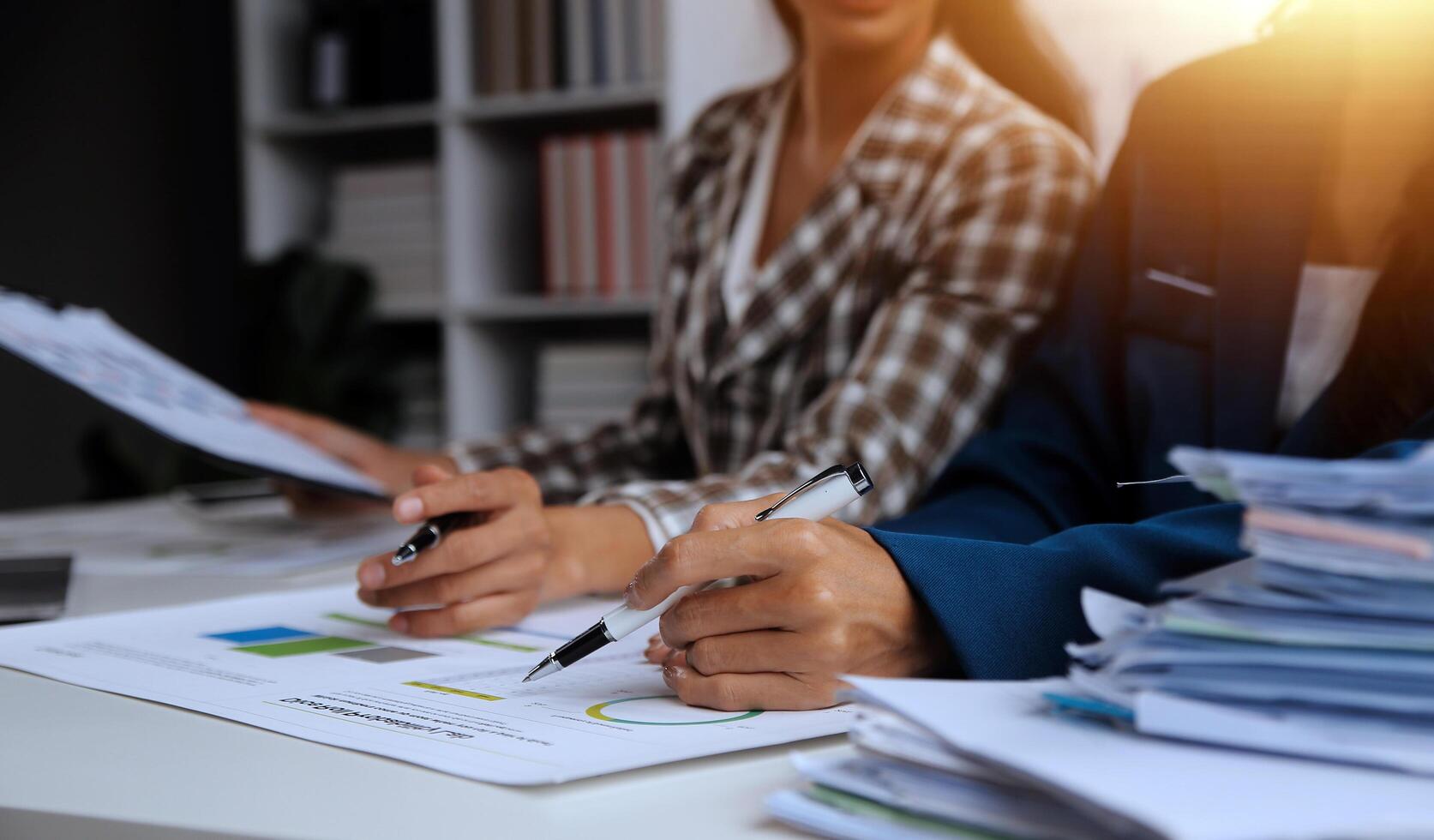 Group of confident business people point to graphs and charts to analyze market data, balance sheet, account, net profit to plan new sales strategies to increase production capacity. photo