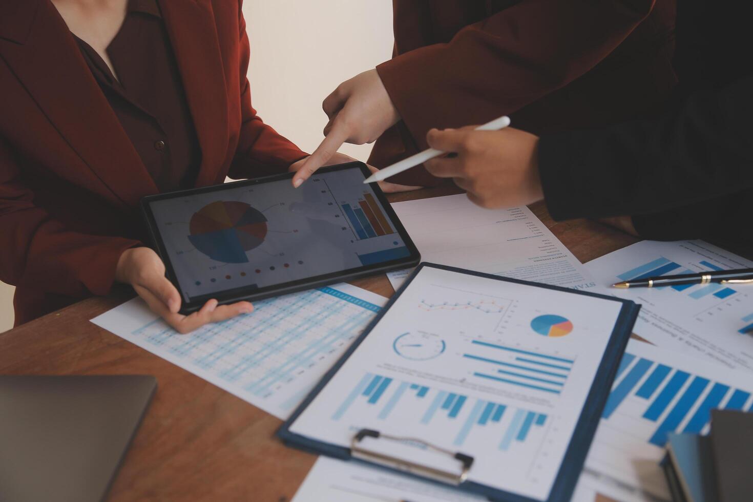 Group of confident business people point to graphs and charts to analyze market data, balance sheet, account, net profit to plan new sales strategies to increase production capacity. photo