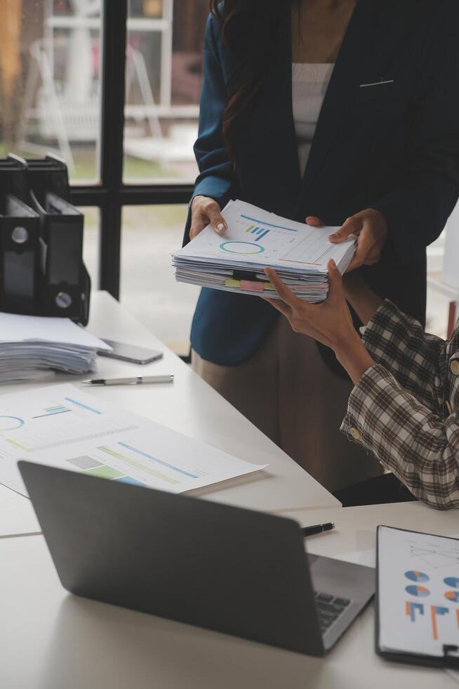 Group of confident business people point to graphs and charts to analyze market data, balance sheet, account, net profit to plan new sales strategies to increase production capacity. photo