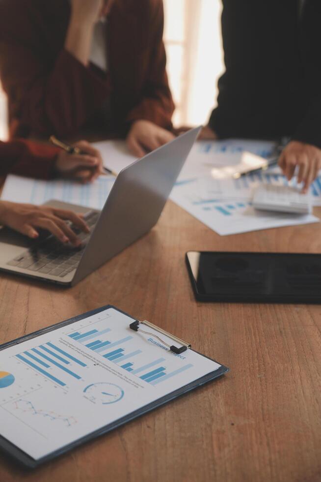 Group of confident business people point to graphs and charts to analyze market data, balance sheet, account, net profit to plan new sales strategies to increase production capacity. photo
