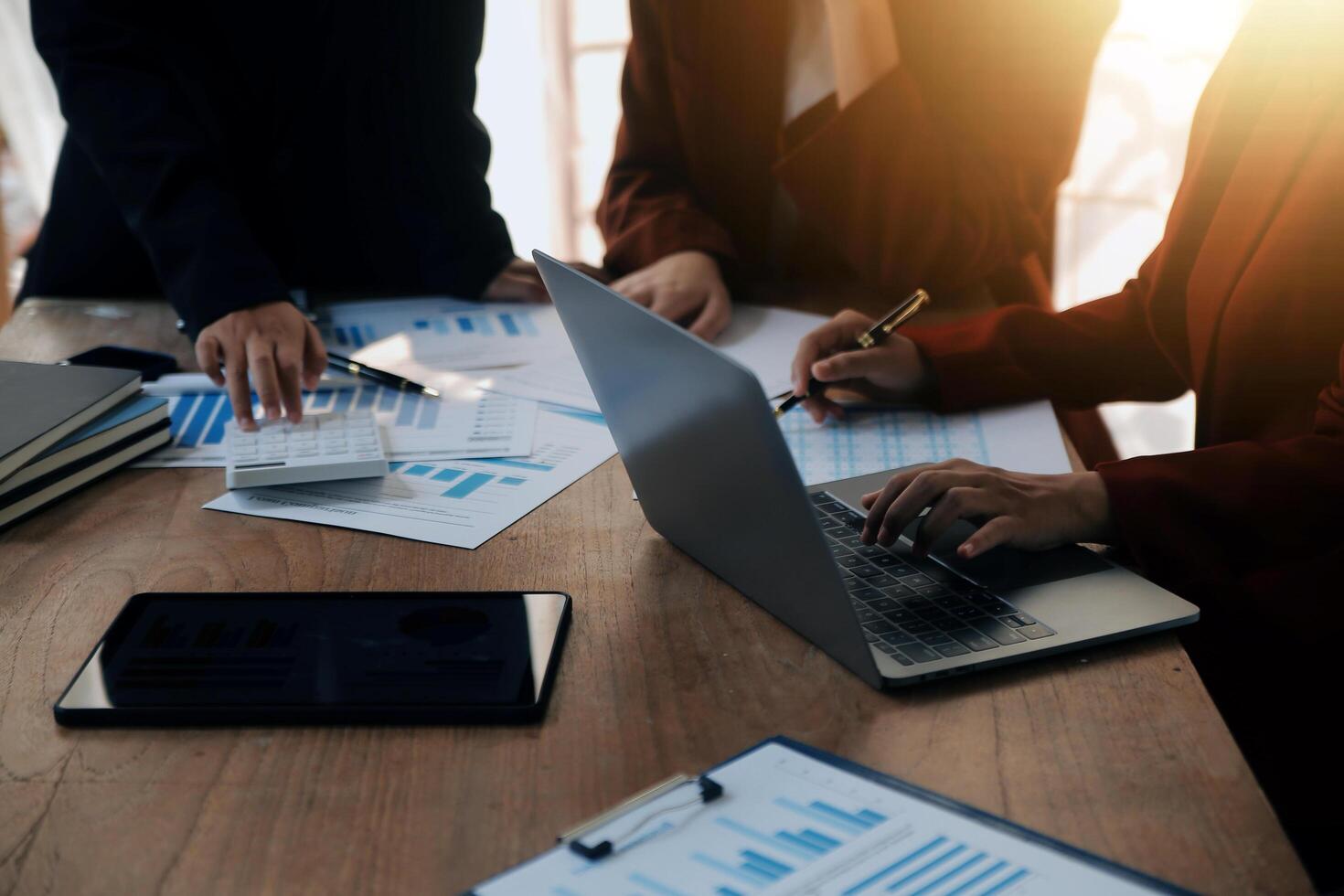 Group of confident business people point to graphs and charts to analyze market data, balance sheet, account, net profit to plan new sales strategies to increase production capacity. photo