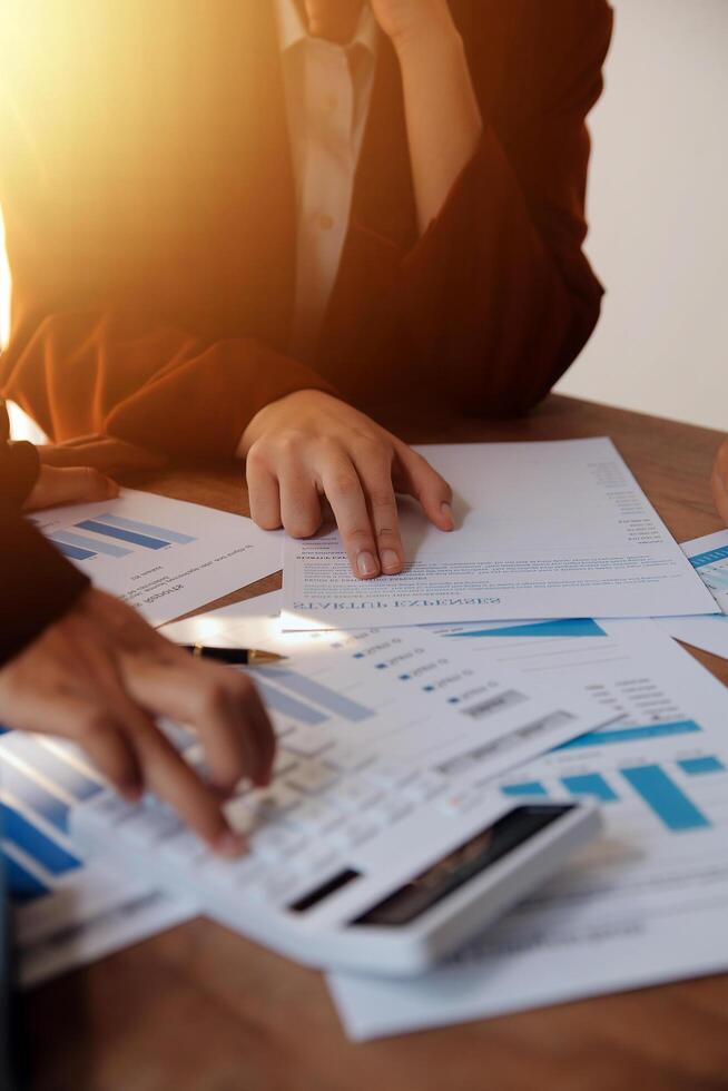 Group of confident business people point to graphs and charts to analyze market data, balance sheet, account, net profit to plan new sales strategies to increase production capacity. photo