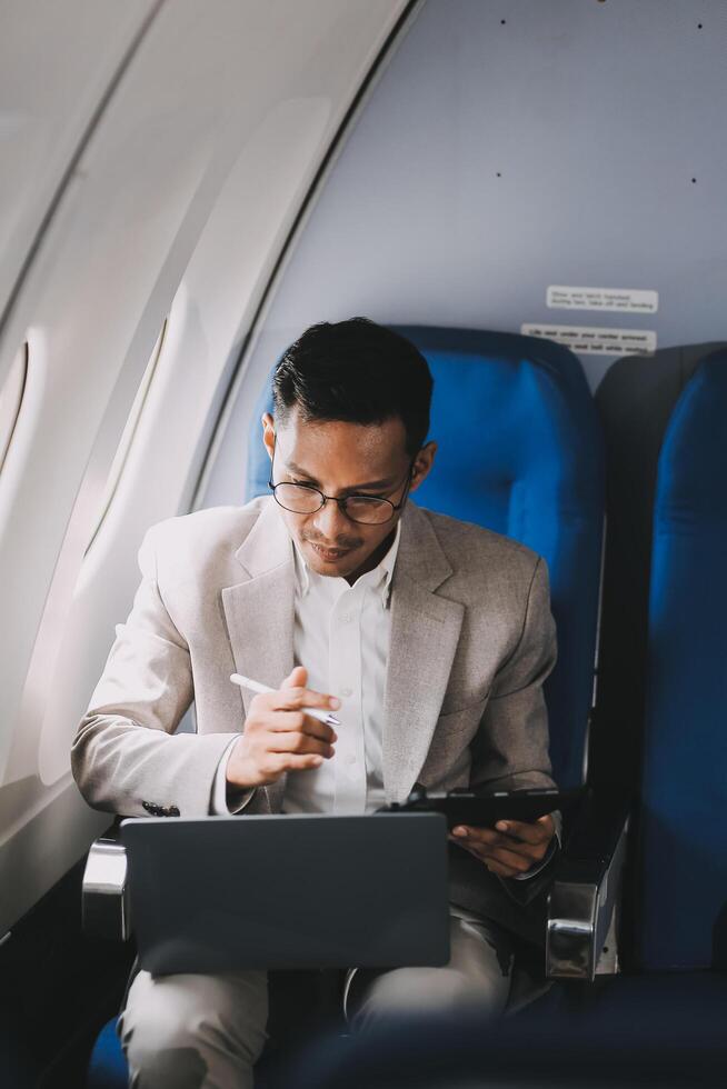 Airplane, travel and portrait of businessman working on laptop computer and smartphone while sitting in airplane. photo