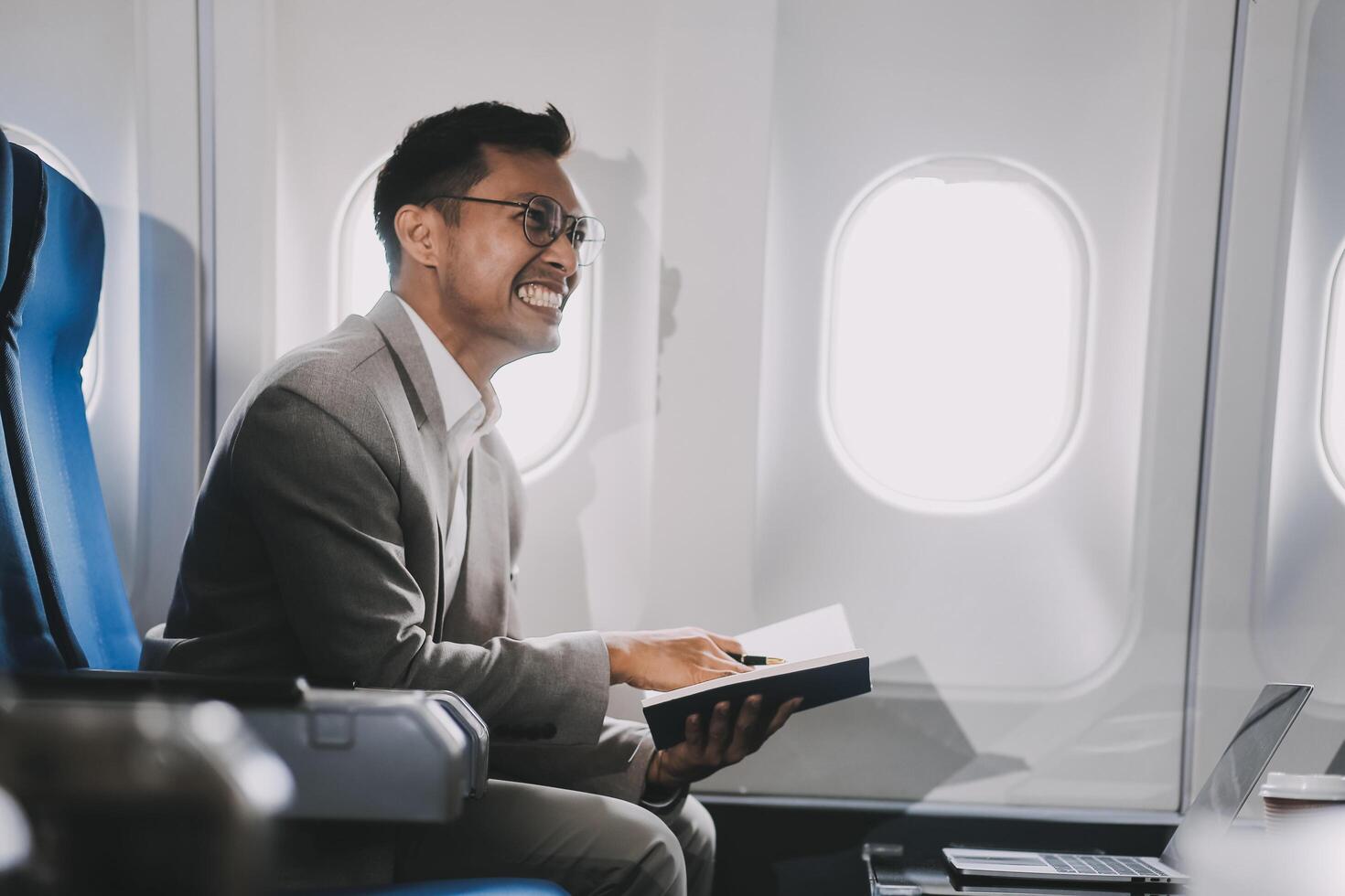 Airplane, travel and portrait of businessman working on laptop computer and smartphone while sitting in airplane. photo