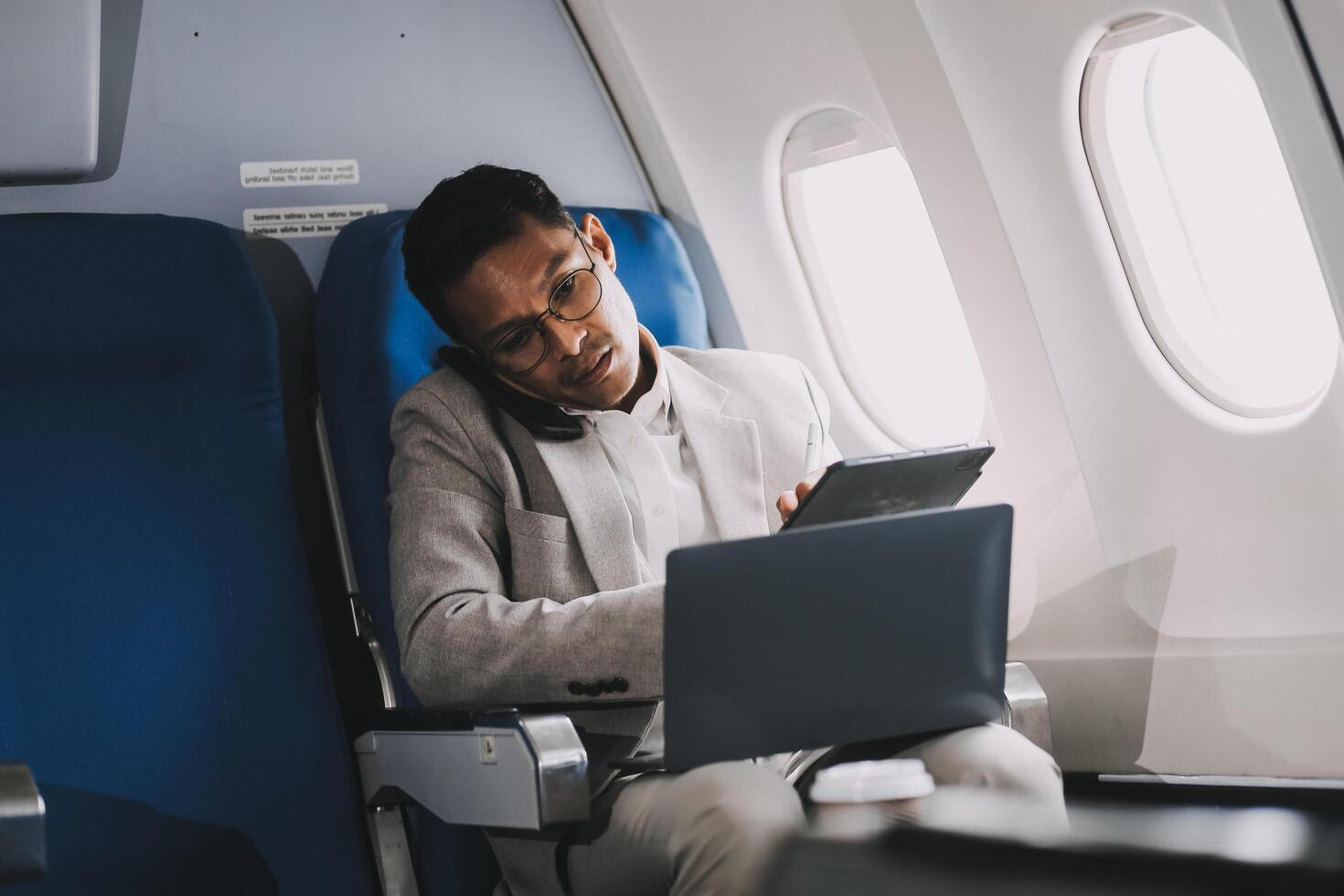 Airplane, travel and portrait of businessman working on laptop computer and smartphone while sitting in airplane. photo