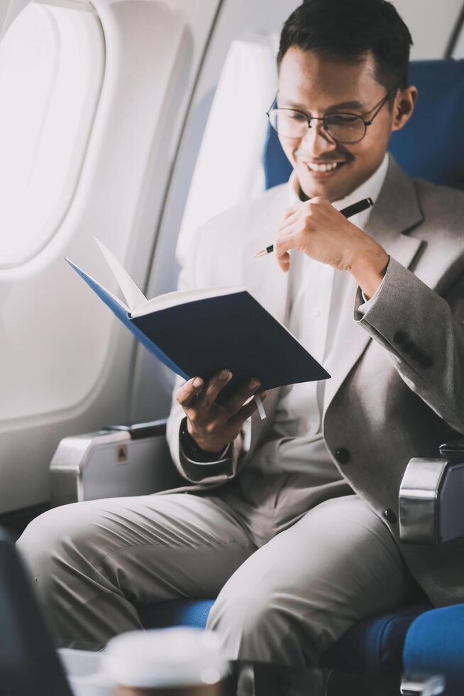 Airplane, travel and portrait of businessman working on laptop computer and smartphone while sitting in airplane. photo