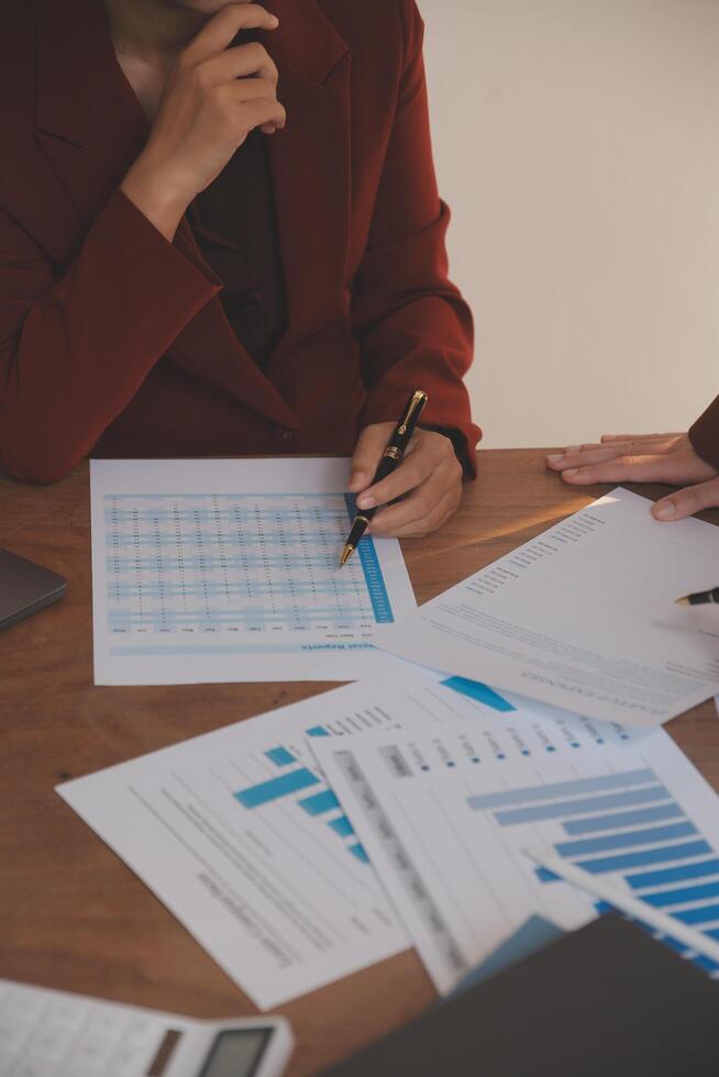 Group of confident business people point to graphs and charts to analyze market data, balance sheet, account, net profit to plan new sales strategies to increase production capacity. photo
