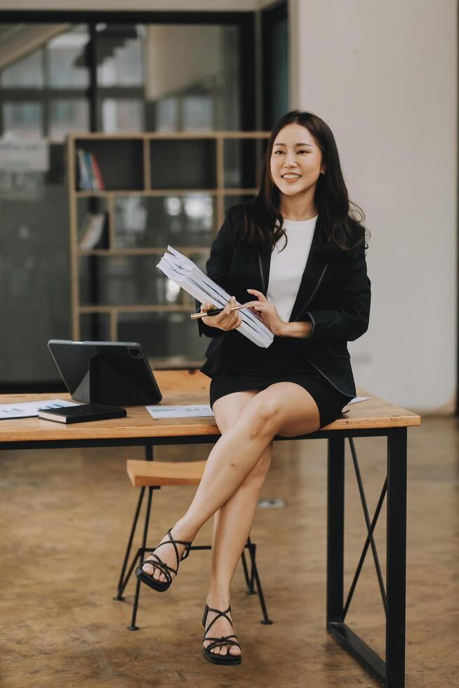 Asian businesswoman talking on phone, using laptop, looking at screen, entrepreneur manager consulting client by call, looking at computer screen, discussing project, reading information photo