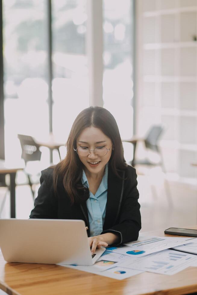 Young beautiful woman typing on tablet and laptop while sitting at the working wooden table modern office photo