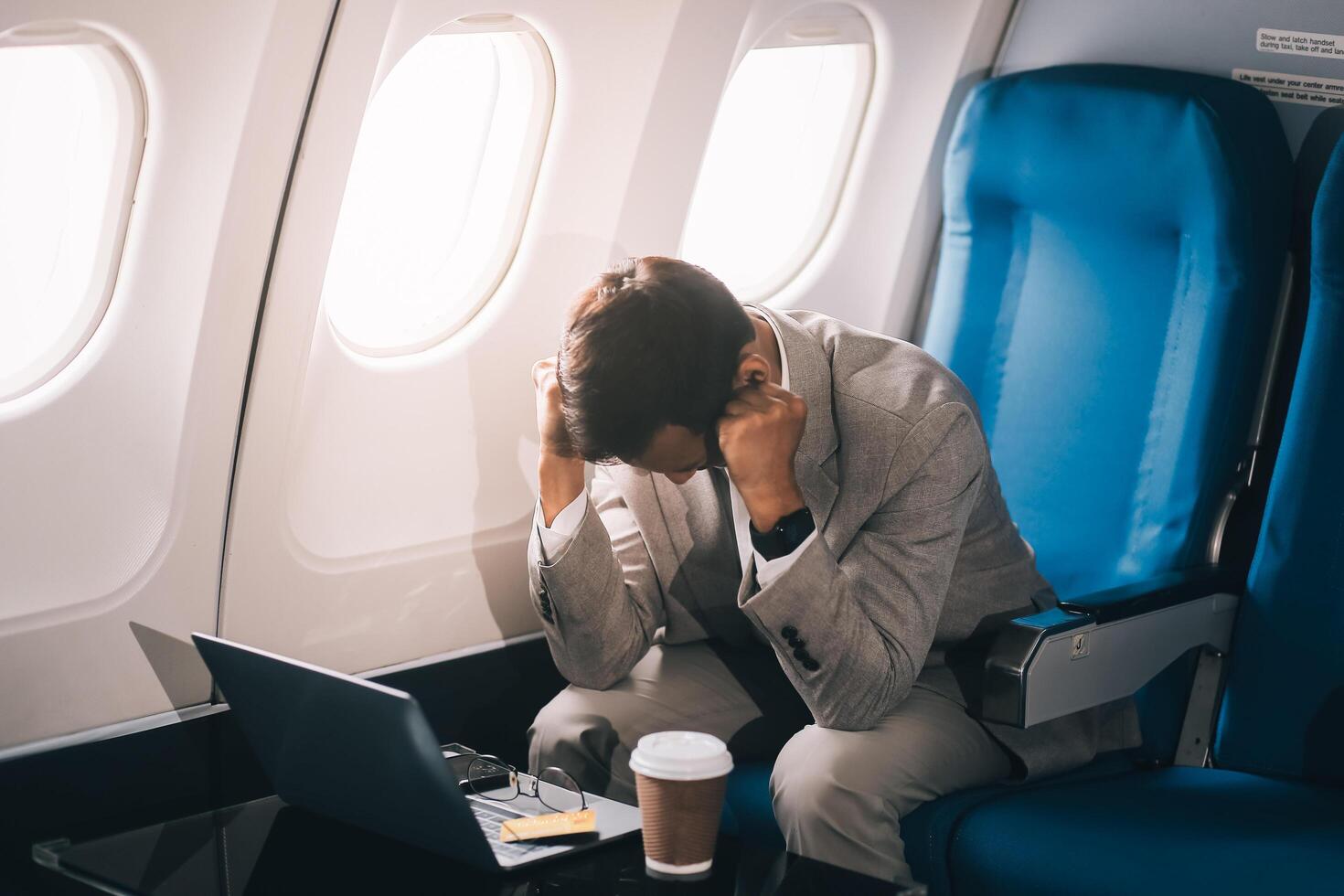 Stressed and professional Asian businessman in a business class, having a serious phone call with someone during the flight to a business meeting. photo