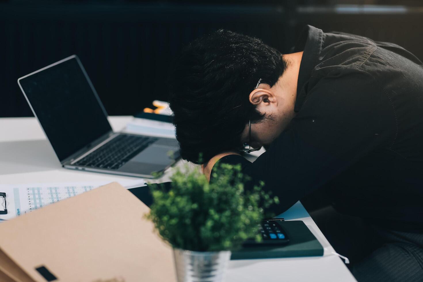 Frustrated Asian young businessman worker working on table in office. Busy employee worker people feel tired and headache from late work and overwork job document on computer desk at company workplace photo