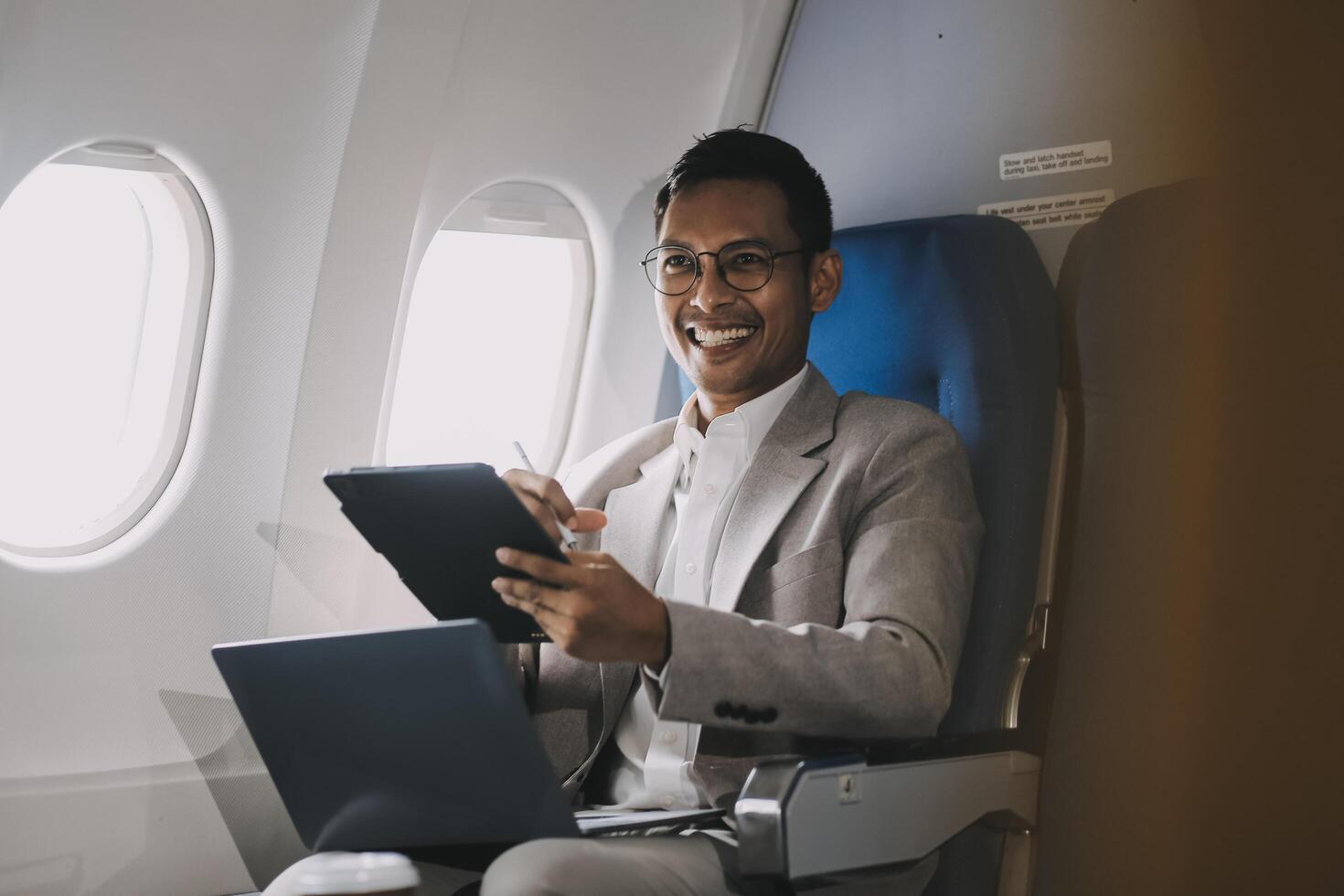 Airplane, travel and portrait of businessman working on laptop computer and smartphone while sitting in airplane. photo