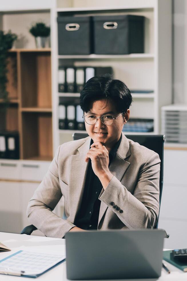 call online meeting asian businessman looking web camera and having fun talking and gesturing, man working inside office sharing plans with partners and colleagues, boss in shirt and glasses. photo