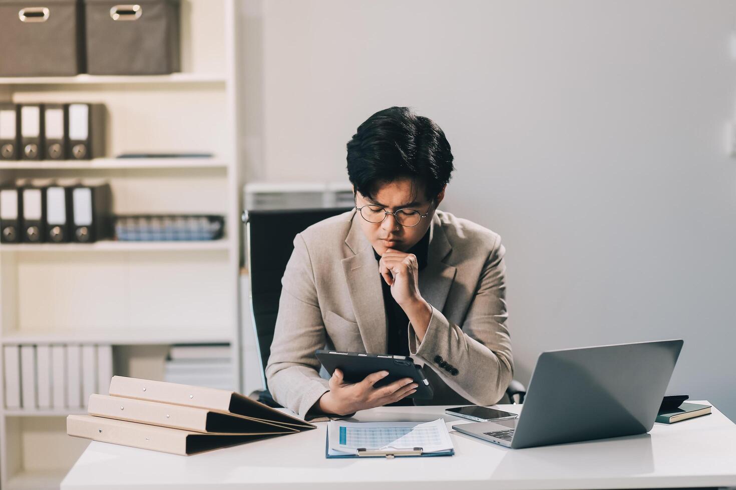 Frustrated Asian young businessman worker working on table in office. Busy employee worker people feel tired and headache from late work and overwork job document on computer desk at company workplace photo