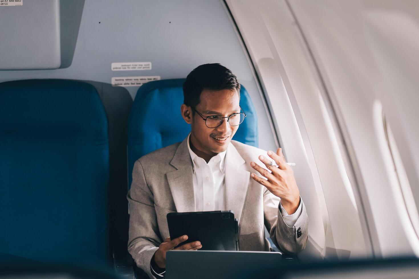 Airplane, travel and portrait of businessman working on laptop computer and smartphone while sitting in airplane. photo