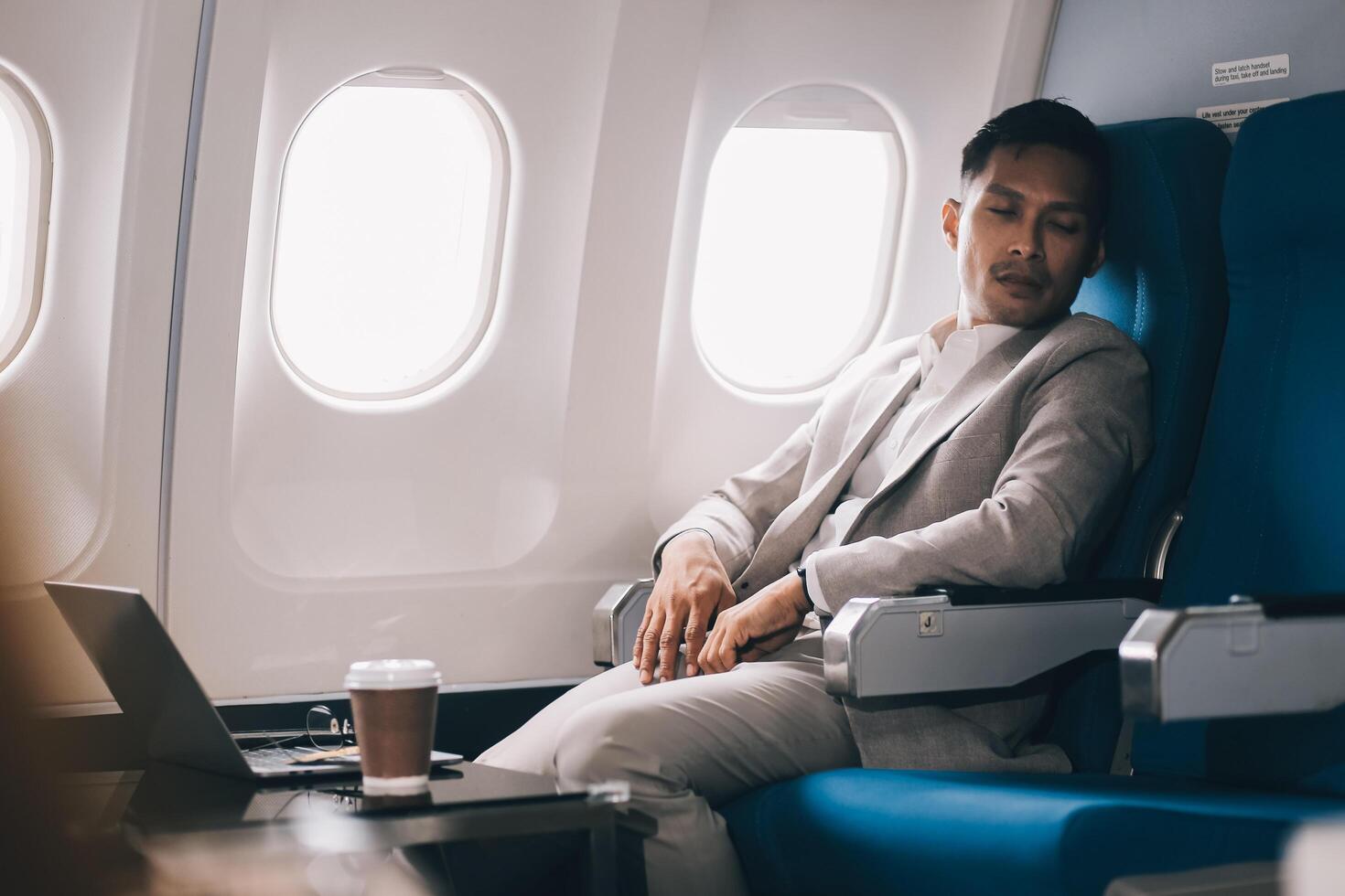 Stressed and professional Asian businessman in a business class, having a serious phone call with someone during the flight to a business meeting. photo