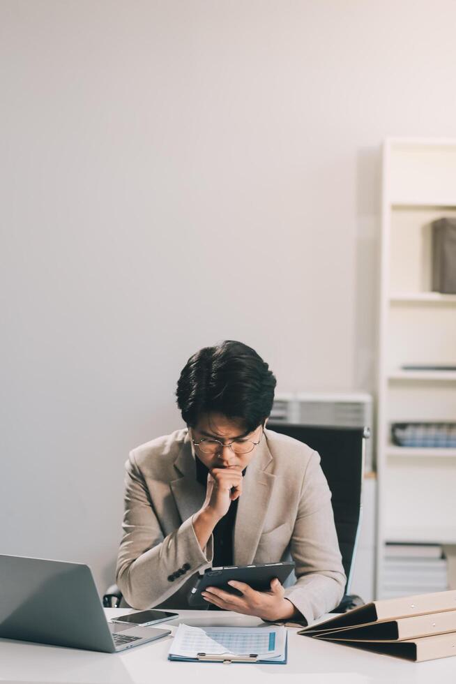 Frustrated Asian young businessman worker working on table in office. Busy employee worker people feel tired and headache from late work and overwork job document on computer desk at company workplace photo