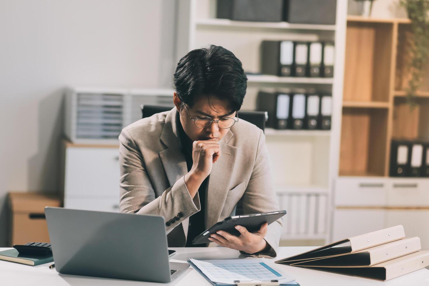 Frustrated Asian young businessman worker working on table in office. Busy employee worker people feel tired and headache from late work and overwork job document on computer desk at company workplace photo