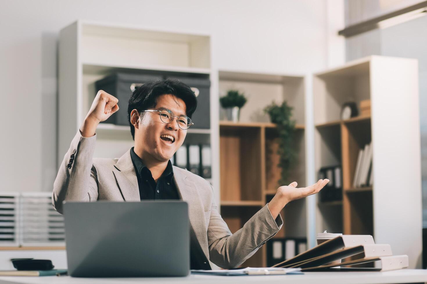 call online meeting asian businessman looking web camera and having fun talking and gesturing, man working inside office sharing plans with partners and colleagues, boss in shirt and glasses. photo