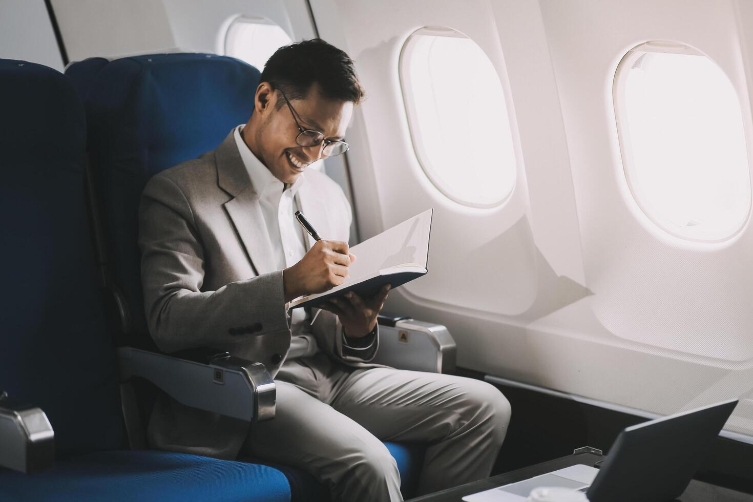 Airplane, travel and portrait of businessman working on laptop computer and smartphone while sitting in airplane. photo