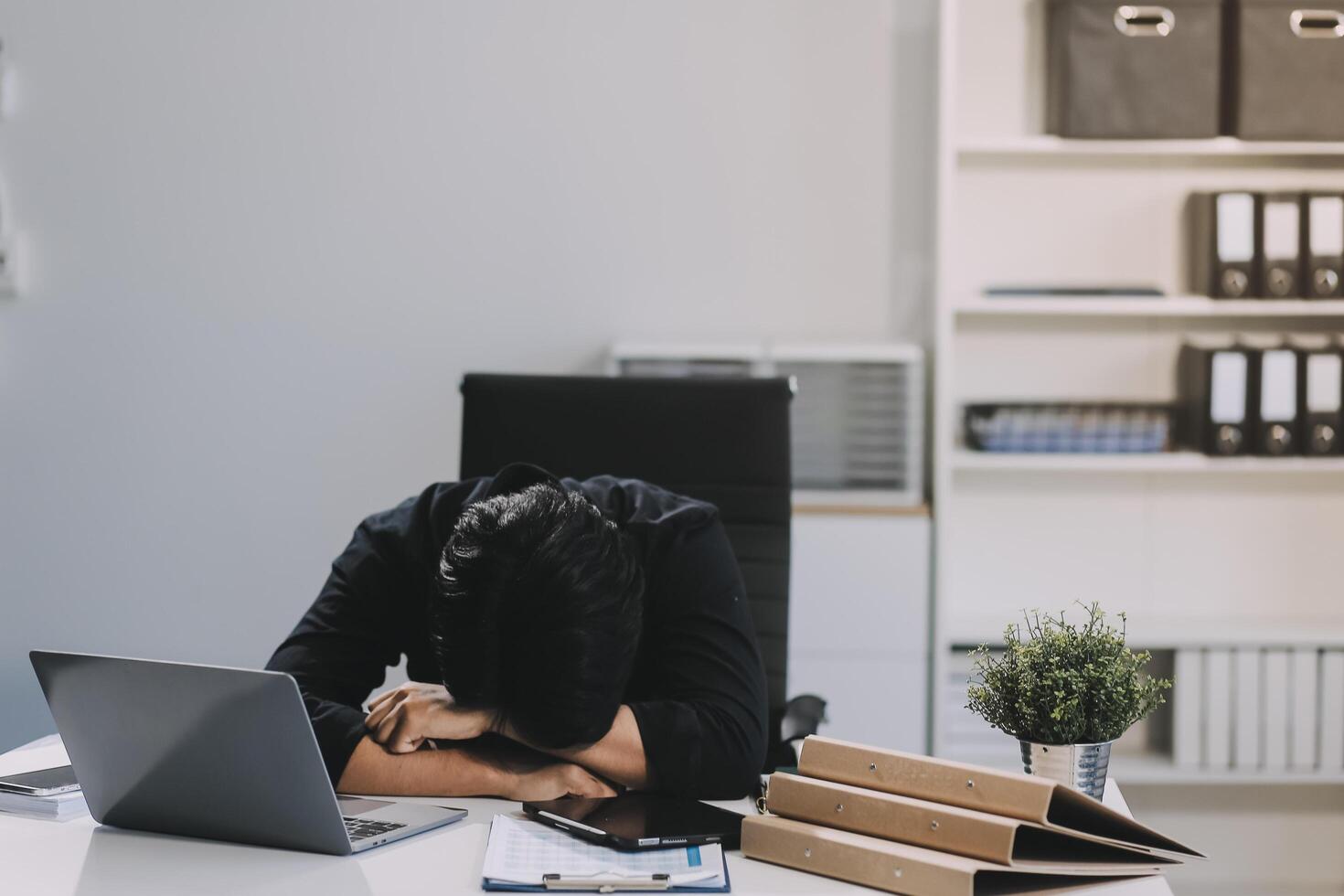 Frustrated Asian young businessman worker working on table in office. Busy employee worker people feel tired and headache from late work and overwork job document on computer desk at company workplace photo