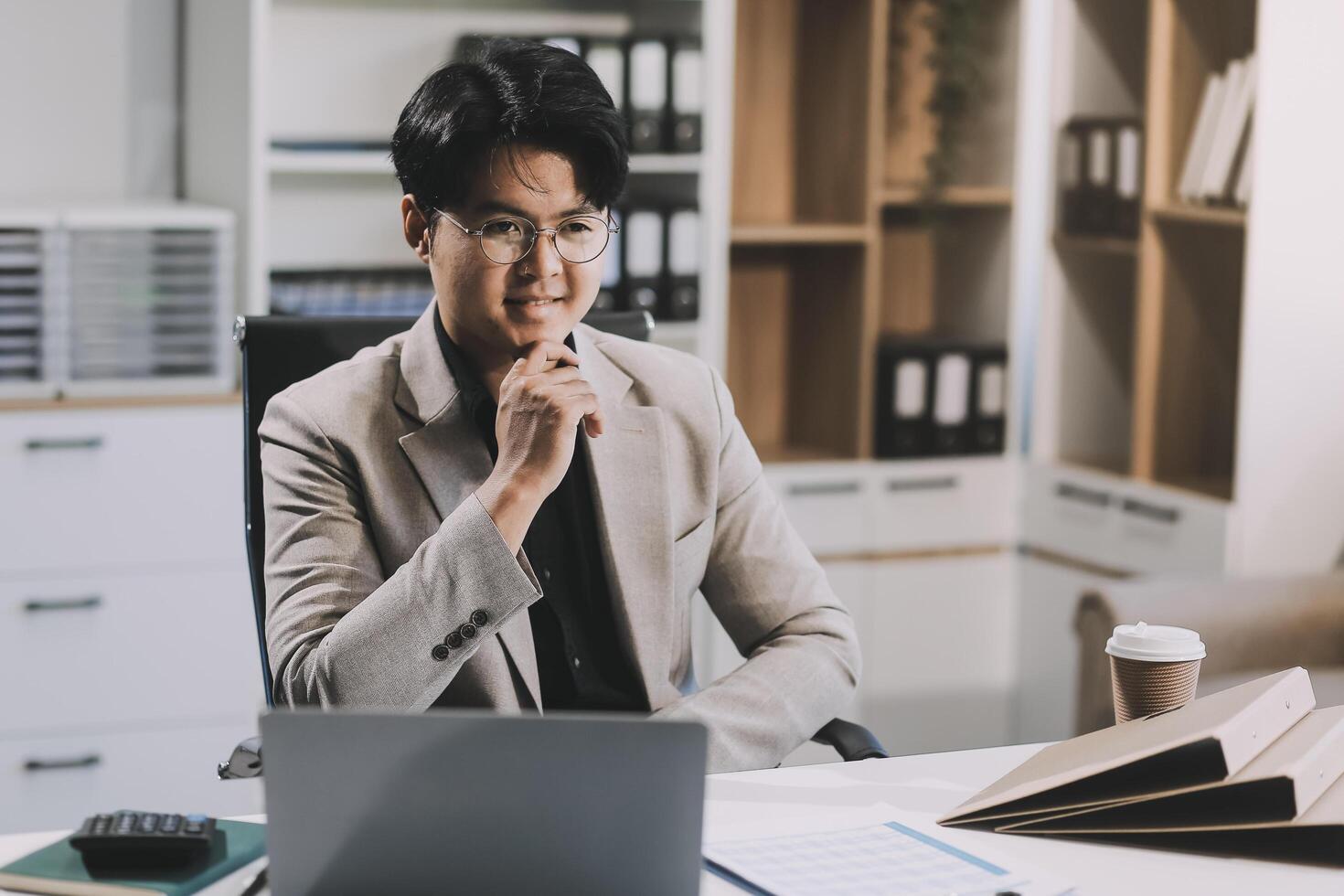 call online meeting asian businessman looking web camera and having fun talking and gesturing, man working inside office sharing plans with partners and colleagues, boss in shirt and glasses. photo