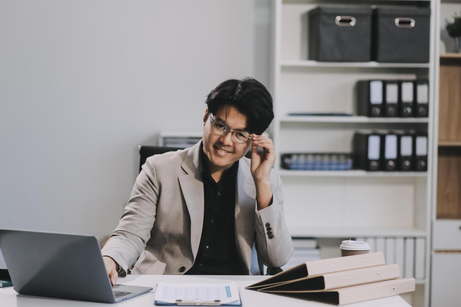 call online meeting asian businessman looking web camera and having fun talking and gesturing, man working inside office sharing plans with partners and colleagues, boss in shirt and glasses. photo