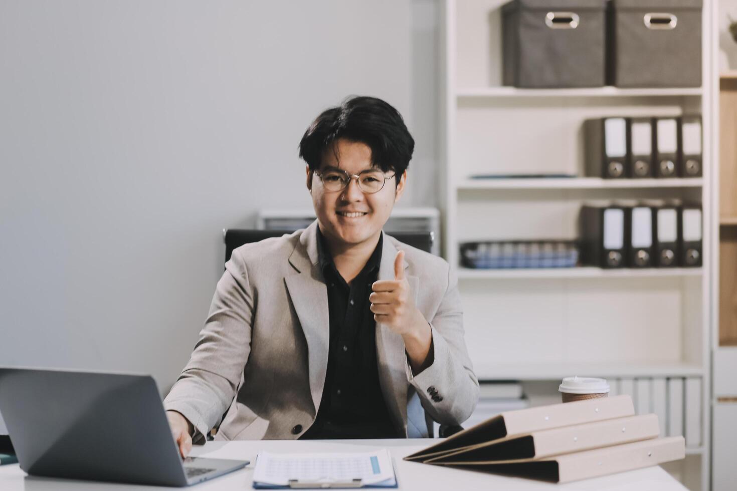 call online meeting asian businessman looking web camera and having fun talking and gesturing, man working inside office sharing plans with partners and colleagues, boss in shirt and glasses. photo