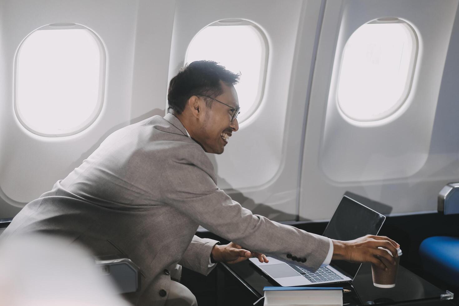 Airplane, travel and portrait of businessman working on laptop computer and smartphone while sitting in airplane. photo