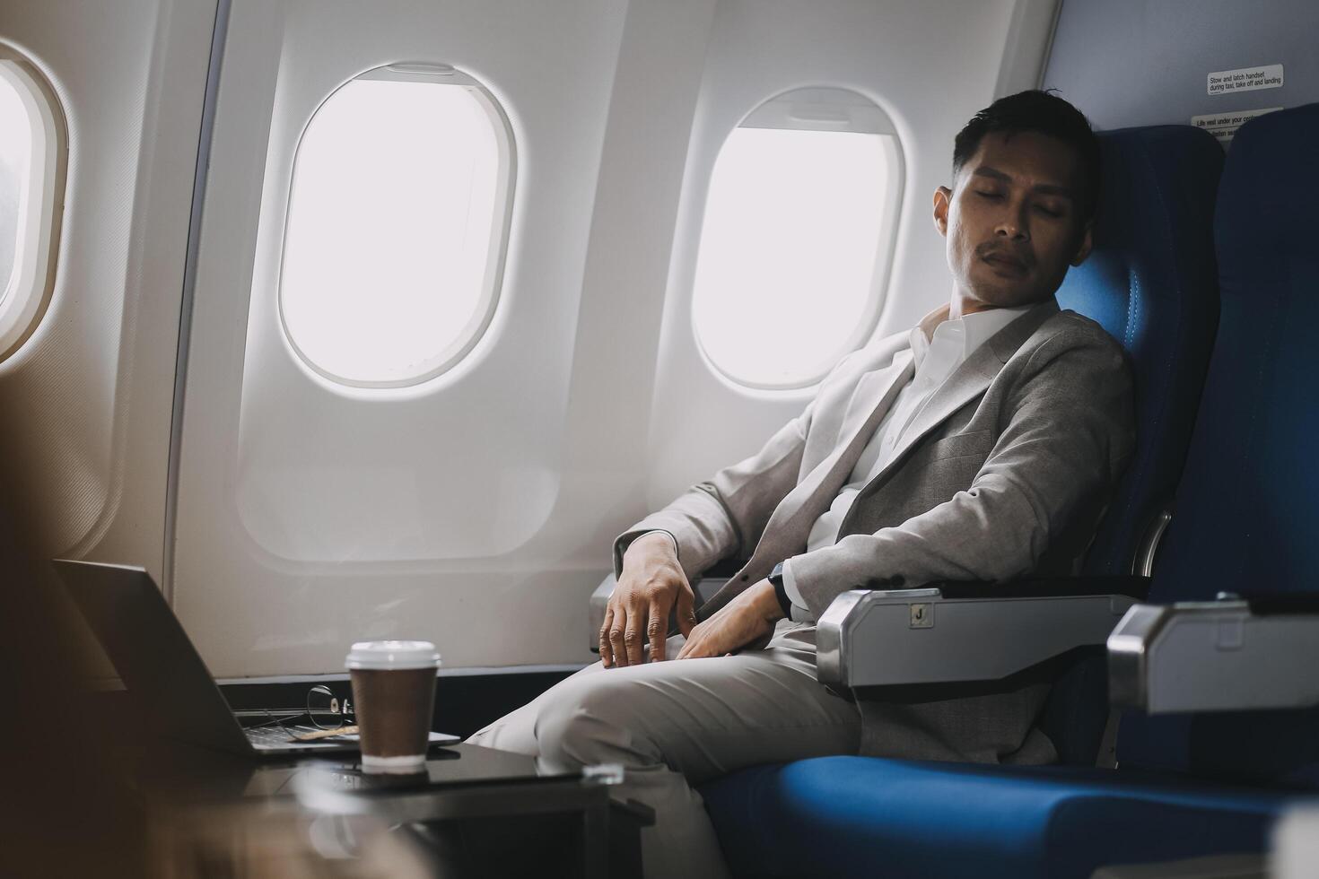 Stressed and professional Asian businessman in a business class, having a serious phone call with someone during the flight to a business meeting. photo