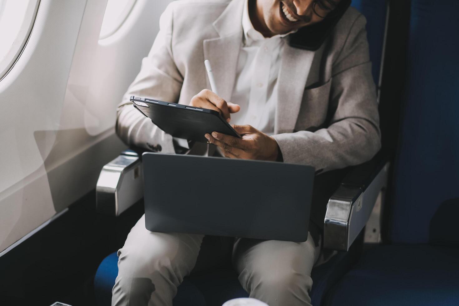 Airplane, travel and portrait of businessman working on laptop computer and smartphone while sitting in airplane. photo