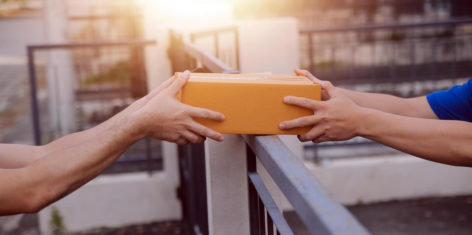 Asian delivery express courier young man use giving boxes to woman customer he wearing protective face mask at front home photo