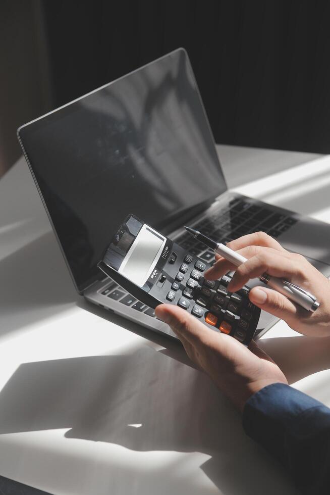 businessman working on desk office with using a calculator to calculate the numbers, finance accounting concept photo